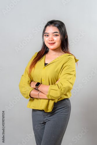 Confident young Asian woman standing with arms crossed and a soft, assured smile. Her calm and professional facial expression suits business, leadership, or branding advertisement themes.