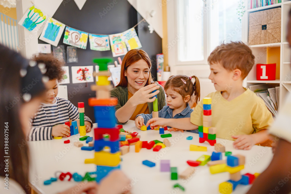 Fototapeta premium Preschool teacher interacts with a diverse group of children building with colorful blocks in a bright classroom, promoting creativity, teamwork, and multicultural early education.