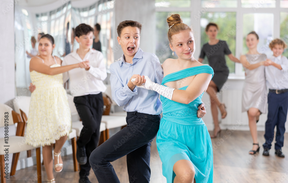 Naklejka premium Positive teen boy and girl are dancing contemporary modern discofox in couple during lesson at studio. Leisure activities and hobby for positive people.