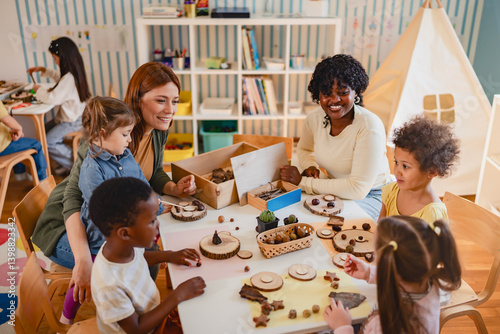 Diverse group of preschool children engage in a nature-based learning activity with two teachers, using wood and natural objects to explore creativity and tactile skills in the classroom.