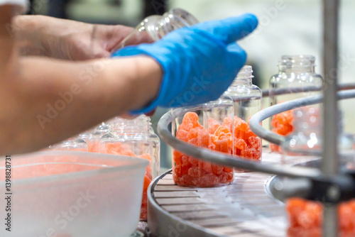 Pharmaceutical employee on an industrial quality control ckecking the production of nutritional gummies on the factory