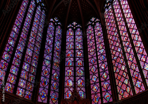 Vibrant stained glass windows illuminate the Gothic interior against a black backdrop.