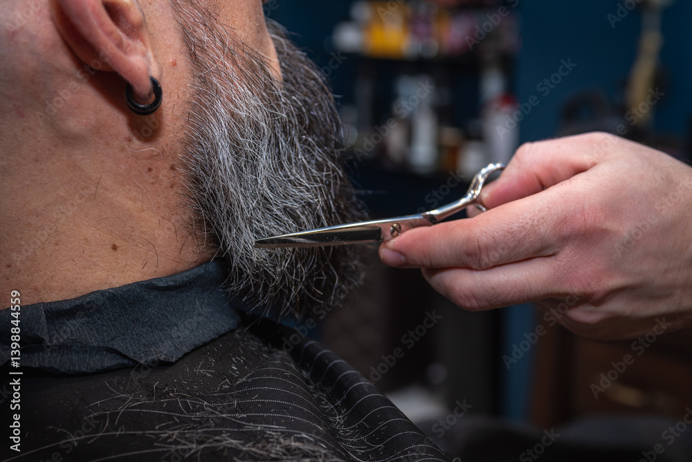 Close-up of a barber trimming a beard with electric clippers in a modern barbershop. Professional men's grooming and beard care service, selective focus
