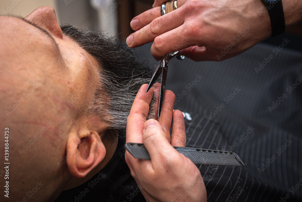 Close-up of a barber trimming a beard with electric clippers in a modern barbershop. Professional men's grooming and beard care service, selective focus
