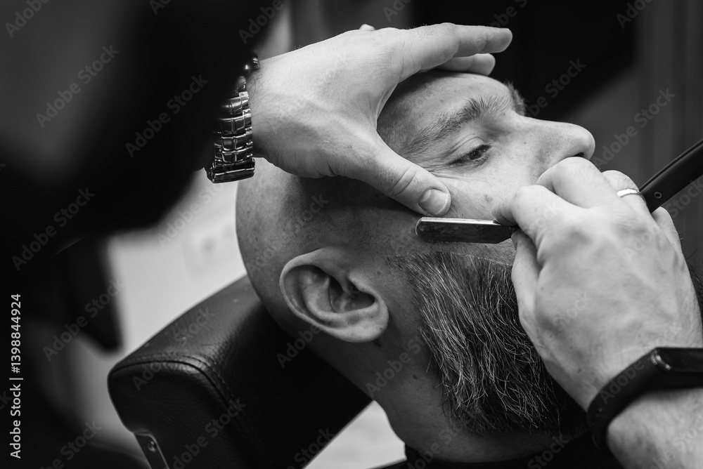 Black and white classic vintage photo, close-up, barber trimming beard with electric clipper, hair scissors in modern barbershop. Professional men's grooming and beard care services, selective focus
