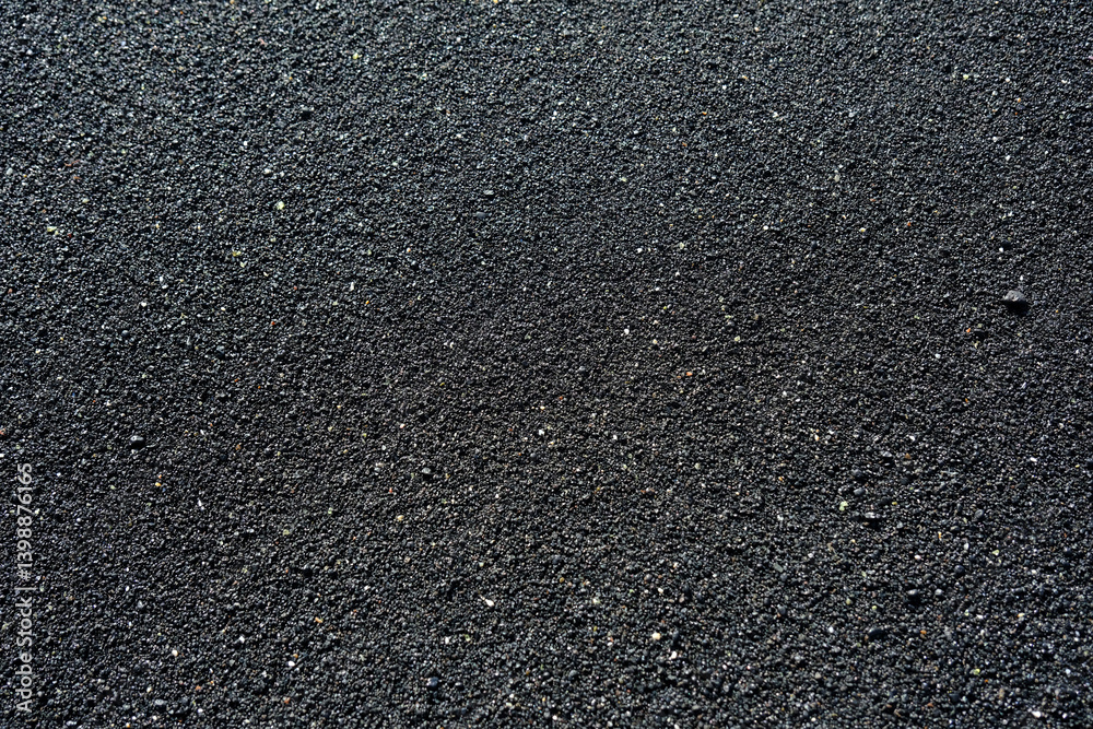 Close-up image of black volcanic sand. The fine, gritty texture and dark tone make it ideal as a natural background or texture for design and creative projects.