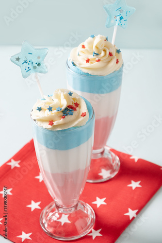 Two layered milkshake or sweet dessert for child on blue background. Food for 4th of July or Memorial Day. Close up.