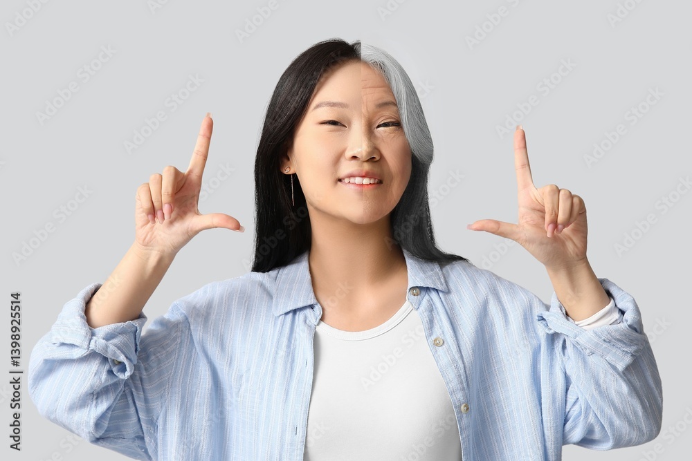 Comparison portrait of young and aged Asian woman pointing at something on grey background Comparison portrait of young and aged Asian woman pointing at something on grey background