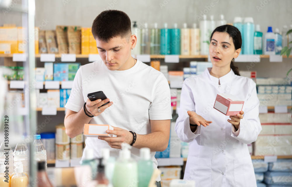 Obraz premium Young man in pharmacy scans QR code tablet medicines product, checks certificate on manufacturers website. Girl pharmacist offer pills analog and support