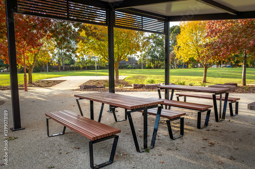 Fototapeta Naklejka Na Ścianę i Meble -  Modern covered picnic area featuring picnic tables and benches under a pavilion.A stylish outdoor dining space offers a public shelter for a community in a suburban neighborhood park in Australia.