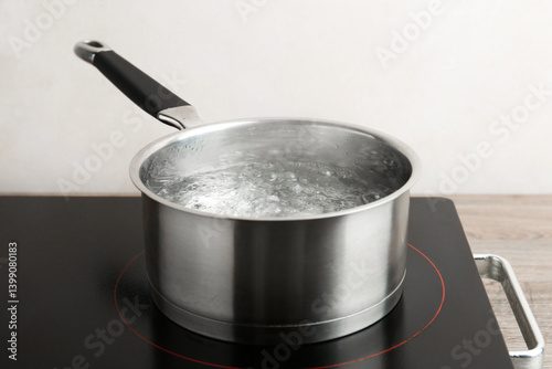Obraz na płótnie Saucepan with boiling water and stove on wooden table against white background, closeup w salonie