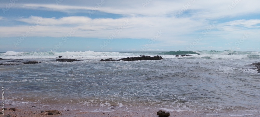 Beach with sea rocks, waves, blue sky and clouds Beach with sea rocks, waves, blue sky and clouds