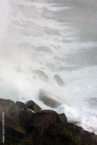 A misty waterfall over large boulders.
