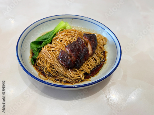 Obraz na płótnie chinese cook hong kong dry wanton roasted bbq char siew meat yellow egg noodle mee in dark soy sauce in plate on white marble table asian restaurant halal food cafe menu w salonie