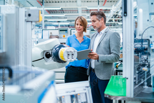 Professionals discussing in a production hall with an industrial robot