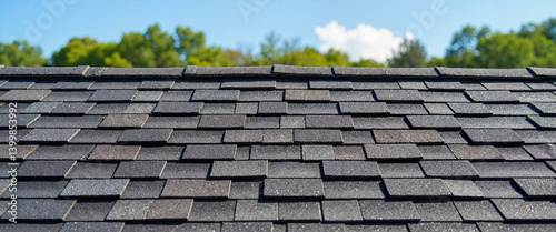 Textured charcoal roof shingles under bright blue sky, natural aging