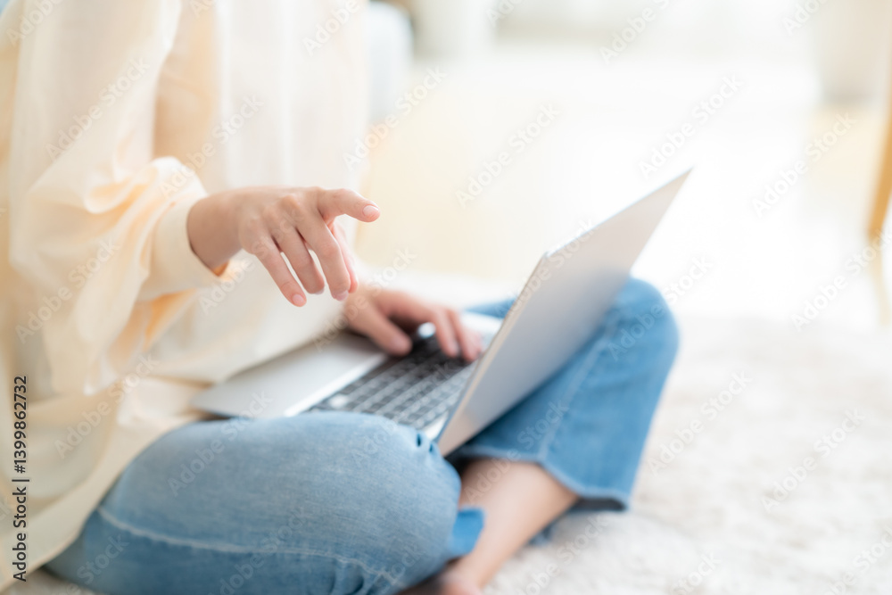Fototapeta premium リビングでパソコンを使う若い女性