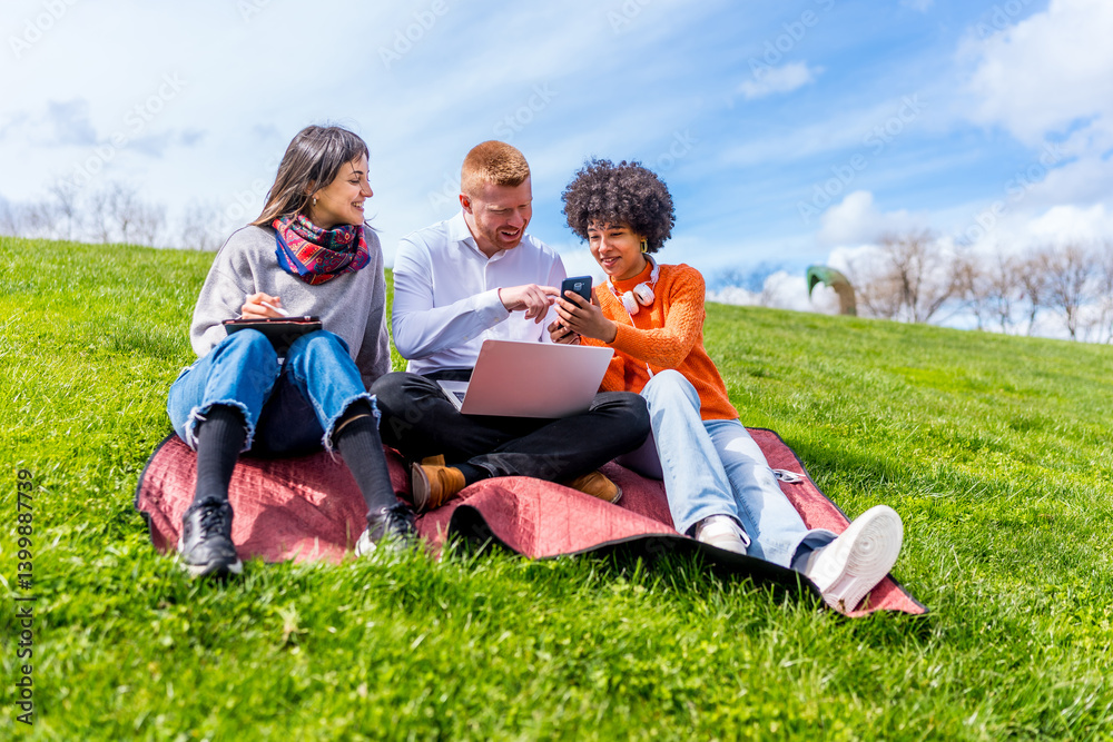 Students using laptop and smartphone, studying outdoor in a park