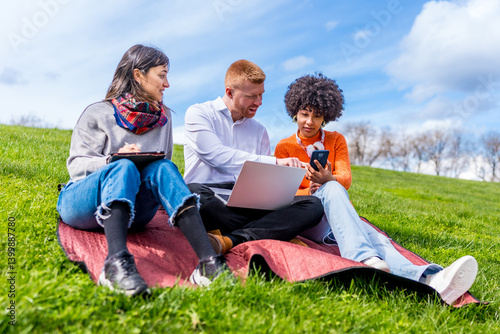 Students working on devices in park on sunny day
