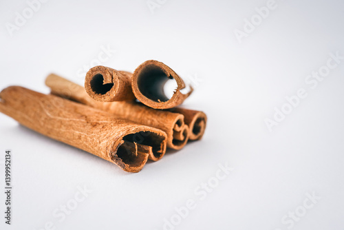 Fototapeta Naklejka Na Ścianę i Meble -  Cinnamon sticks arranged on a white background in soft natural light, showcasing texture and spice detail