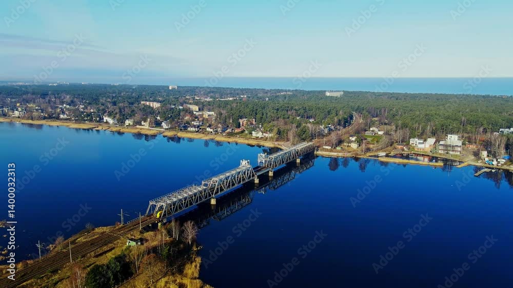Electric train from Riga crosses steel Lielupe bridge on a bright spring morning Electric train from Riga crosses steel Lielupe bridge on a bright spring morning