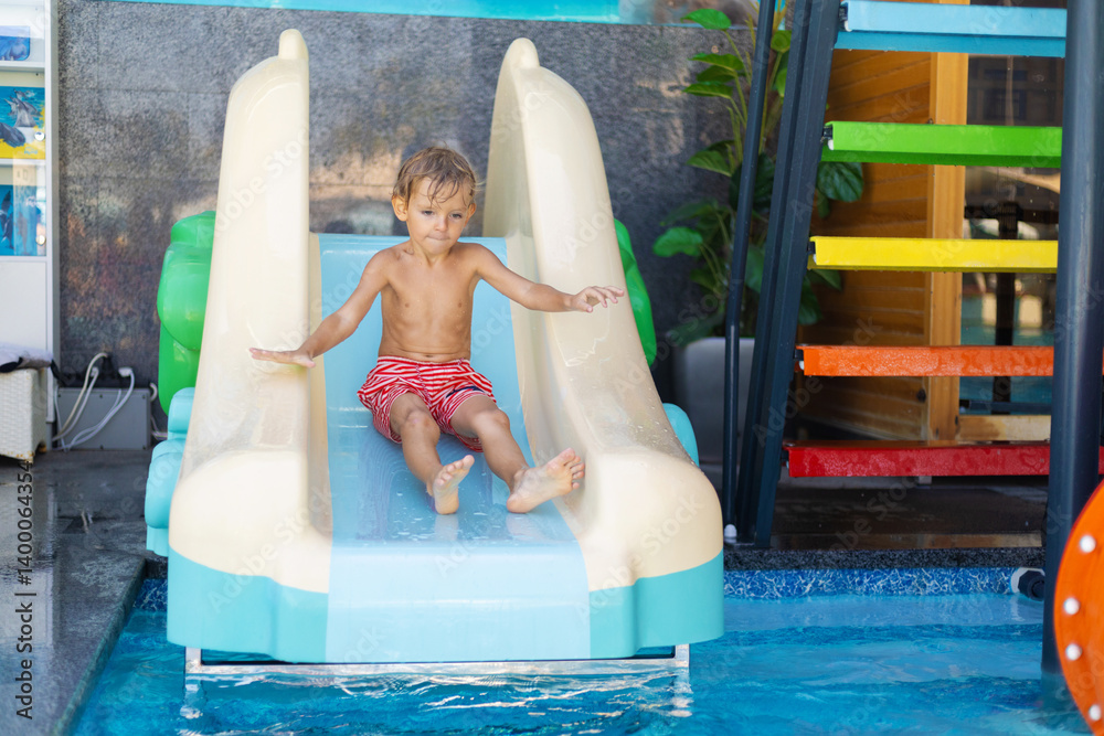 Child sliding down into swimming pool