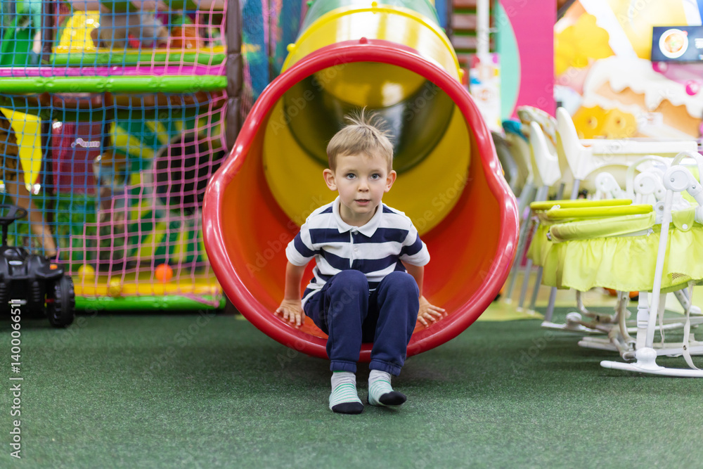 Boy sliding out of indoor tube slide