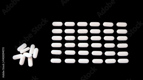 Oval white supplement tablets, arranged neatly in rows, with a small pile on the left. With black background.