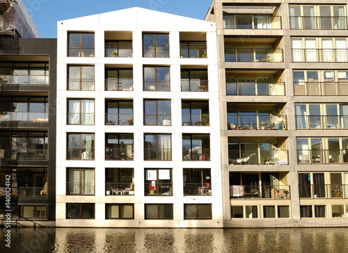 Valokuvatapetti Modern white apartment building with balconies reflecting in the calm water of a canal in the Netherlands