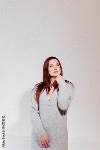 Obraz na płótnie Attractive brunette woman in grey dress against white wall. w salonie