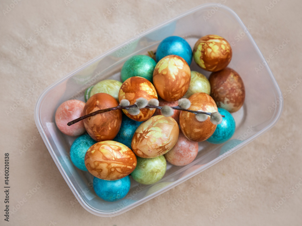 Obraz premium Dyed chicken eggs and a sprig of willow lay on a beige background.