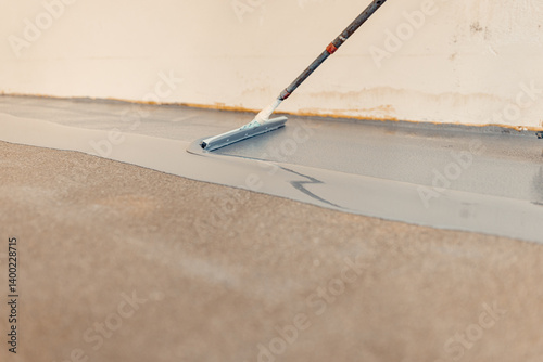 Construction worker applying epoxy resin on concrete floor