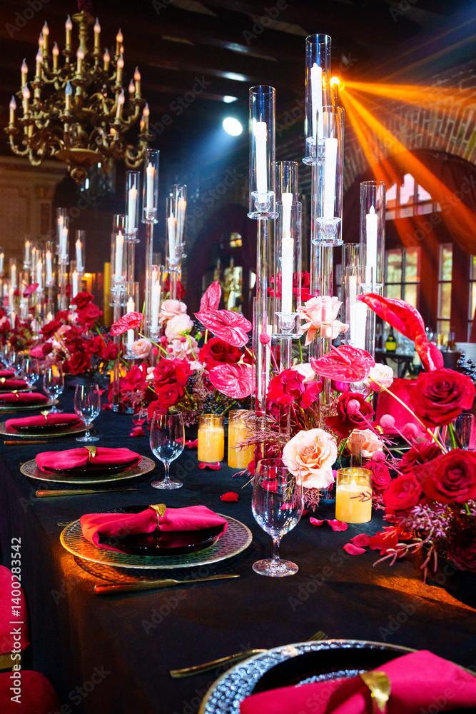 Beautiful festive table setting with fresh red flowers, napkins and candles.