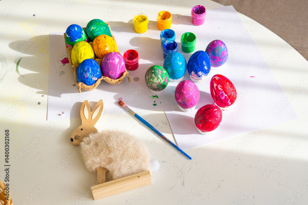 Colorful egg decorating activity with paints and adorable rabbit craft on a bright table in springtime