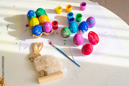 Obraz na płótnie Colorful egg decorating activity with paints and adorable rabbit craft on a bright table in springtime w salonie
