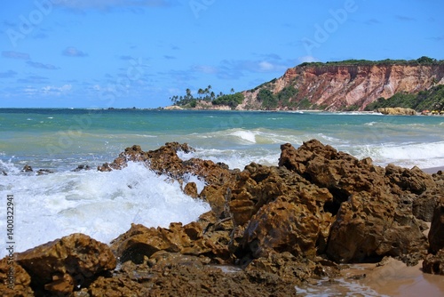 Tabatinga beach close to Joao Pessoa city, Paraiba state, Brazil northeast. Tropical seascape with waves crashing on rocks, blue sea, coloroful cliffs on horizon line. Toutistic place 