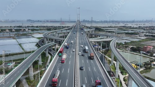 Multi-level bridge China. Cars drive transport interchange. Road traffic. Chinese ship sails, freight cargo logistic. Aerial top drone view, fast urban highway. Modern city freeway. Shipping delivery.