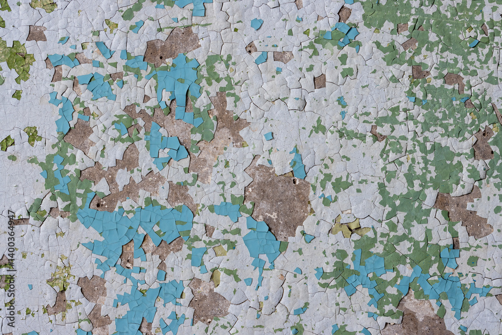 Peeling paint on the wall. Old concrete wall with cracked flaking paint. Weathered rough painted surface with patterns of cracks and peeling. Grunge texture for background and design. High resolution.