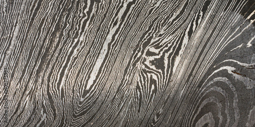 Detailed close up of damascus steel, showcasing its characteristic wavy and layered pattern of light and dark metal. photo