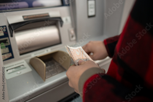 Obraz na płótnie A close-up shot of a man withdrawing cash from an ATM, highlighting the transaction process. A moment of everyday banking, showing the use of technology in personal finance w salonie