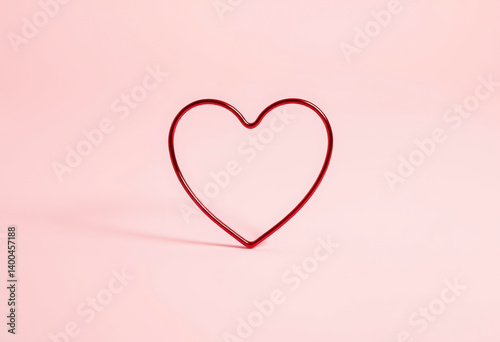Bright red heart shape sits alone on a soft pink background, perfect for conveying love and affection in design projects.