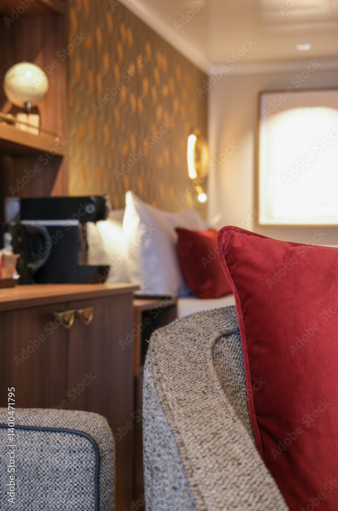 Luxurious mini suite stateroom cabin room onboard luxury cruise ship cruiseship ocean liner with bedroom and living area in red and creme with wood in modern Art Deco interior design