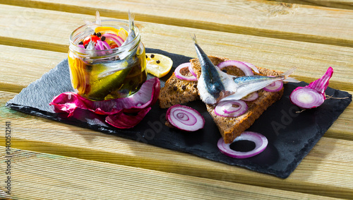 Homemade salting sardines with onions, beets, mixture of peppers and marinade of vinegar, lemon, olive oil and sea salt. Served on black bread with onions.