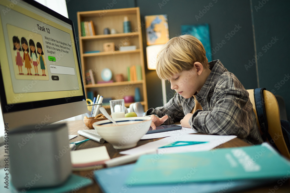 Young boy concentrating on drawing with tablet on study desk, surrounded by books and computer in cozy home study room Young boy concentrating on drawing with tablet on study desk, surrounded by books and computer in cozy home study room