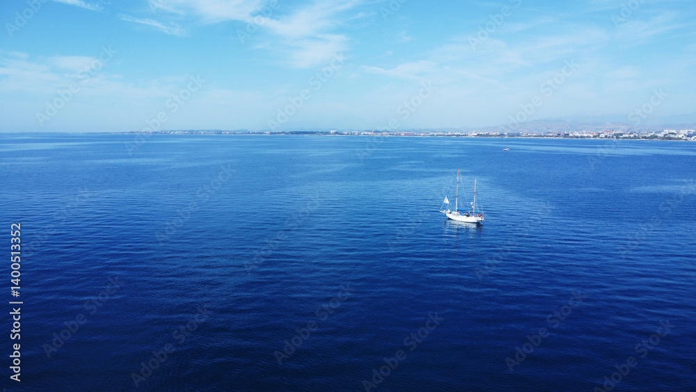Sailboat on a Calm Blue Sea with Distant Coastline Sailboat on a Calm Blue Sea with Distant Coastline