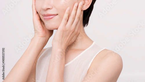 両手で頬を触っているアジア人女性。スキンケア。