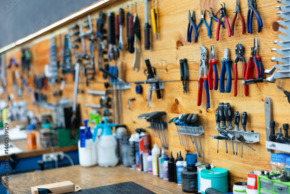 Variety of hand tools for bicycle repair neatly arranged on wooden wall in specialized professional bike workshop