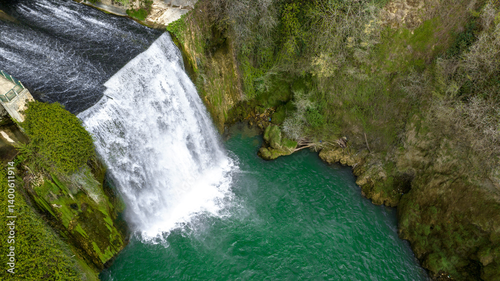 Aerial view of a small waterfall flowing into a pond.