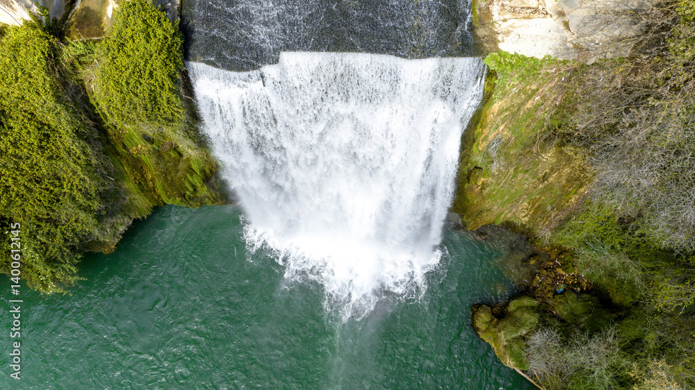 Aerial view of a small waterfall flowing into a pond.