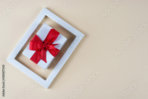 Obraz na płótnie white gift box with red bow in white photo frame w salonie